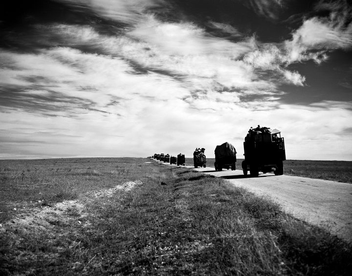 Caravana de camiones cargados con familias desplazadas, en un camino